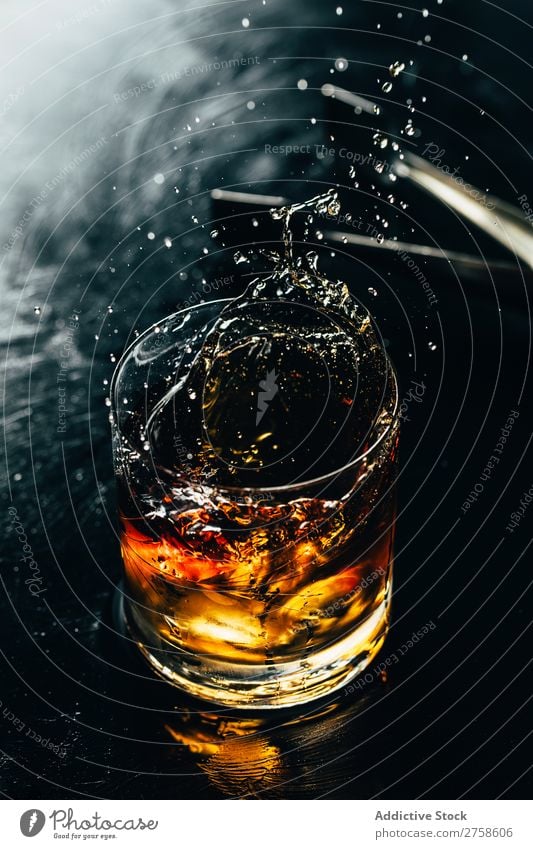 Ein Glas spritzender Whiskey Alkohol Getränk Bourbon braun Cocktail kalt Coolness Kristalle Würfel dunkel trinken Tropfen elegant Vogelperspektive Glaswaren Eis