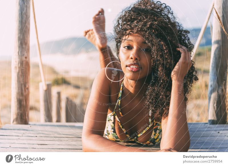 Schöne junge schwarze Frau, die in einer hölzernen Fußgängerbrücke am Strand liegt. Hintergrundbild Bikini Brücke Küste krause Haare Ausflugsziel Mädchen