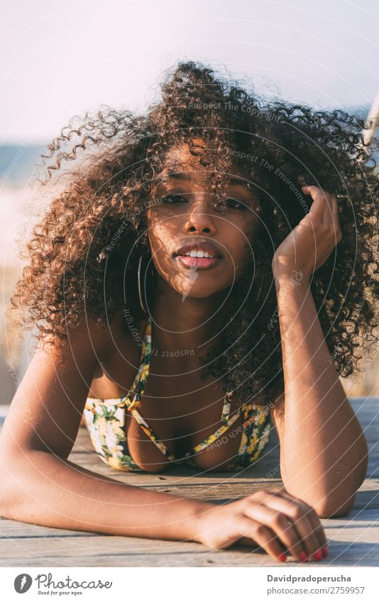 Schöne junge schwarze Frau, die in einer hölzernen Fußgängerbrücke am Strand liegt. Hintergrundbild Bikini Brücke Küste krause Haare Ausflugsziel Mädchen