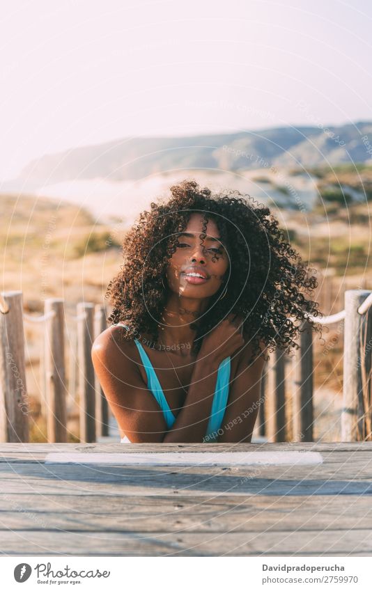 Schöne junge schwarze Frau, die in einer hölzernen Fußgängerbrücke am Strand liegt. Hintergrundbild Bikini Brücke Küste krause Haare Ausflugsziel Mädchen