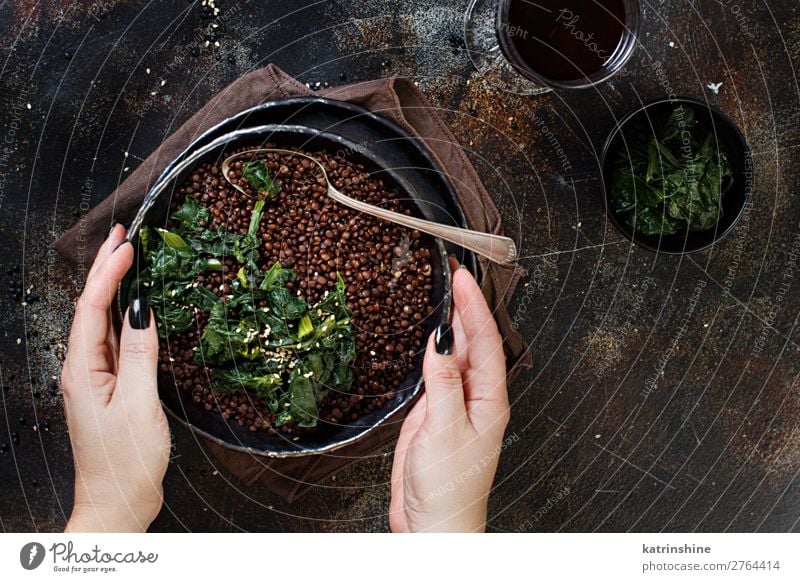 Eintopf mit schwarzen Linsen und Gemüse Vegetarische Ernährung Teller Löffel Hand dunkel oben Hülsenfrüchte schmoren Beluga Spinat Vegane Ernährung essen