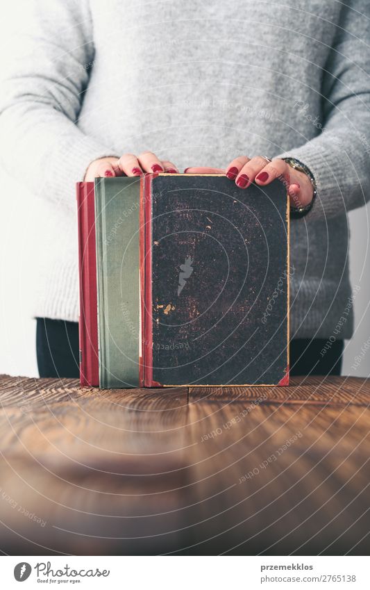 Junge Frau hält alte Bücher auf dem Tisch im Antiquariat. Lifestyle kaufen Erholung Freizeit & Hobby lesen Schule lernen Mensch Erwachsene Jugendliche Buch