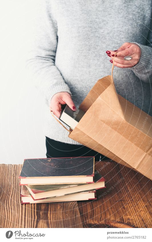 Junge Frau, die alte Bücher in die Papiertasche im Antiquariat bringt. Lifestyle kaufen Erholung Freizeit & Hobby lesen Schule lernen Mensch Erwachsene