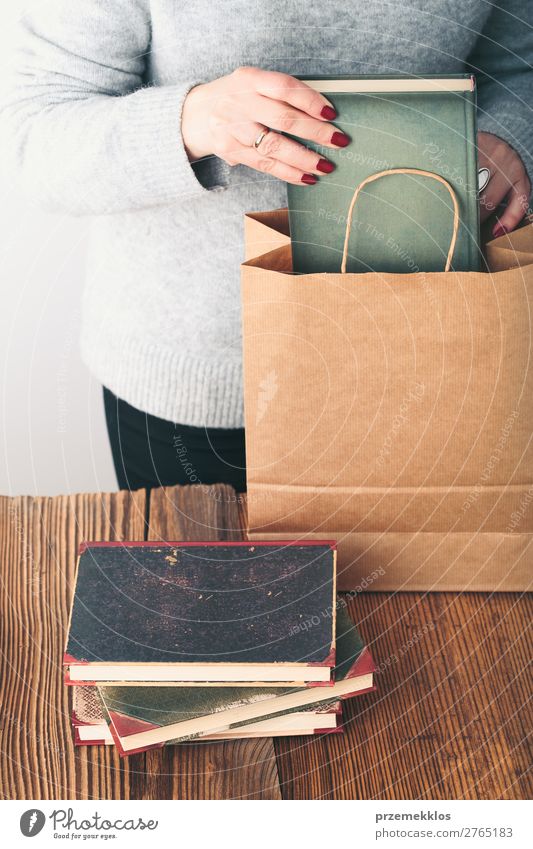 Junge Frau, die alte Bücher in die Papiertasche im Antiquariat bringt. Lifestyle kaufen Erholung Freizeit & Hobby lesen Schule lernen Mensch Erwachsene