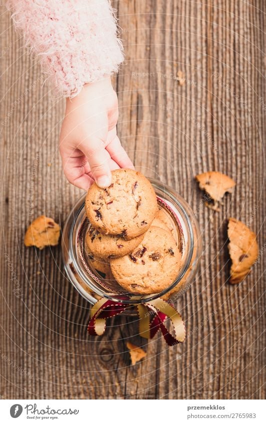 Kleines Mädchen nimmt einen Keks aus einem mit Haferkeksen gefüllten Glas. Dessert Ernährung Essen Diät Lifestyle Tisch Kind Frau Erwachsene Hand genießen