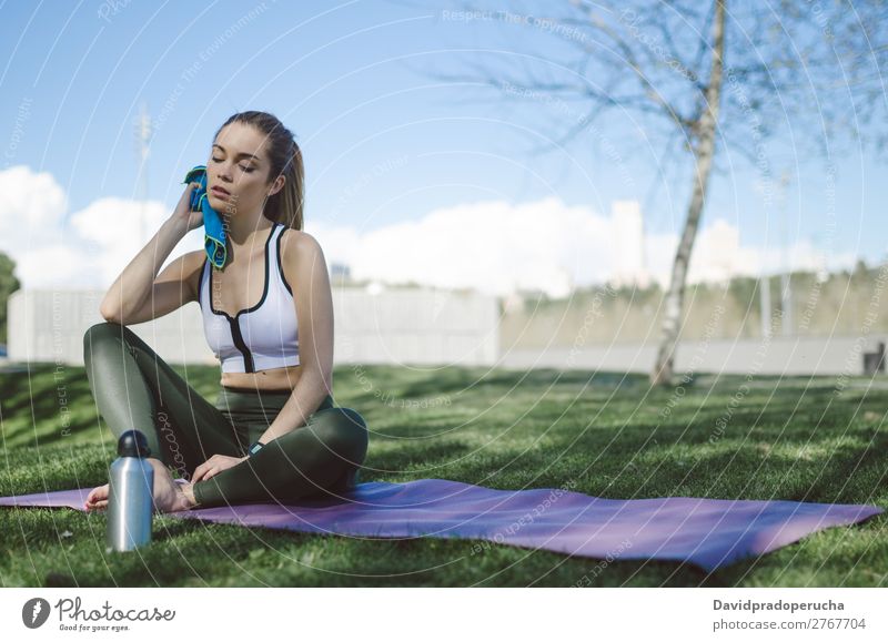 Frau ruht sich aus und trinkt Wasser mit Handtuch nach dem Training. Lifestyle schön Körper Erholung Meditation Sport Yoga Mensch Erwachsene Natur Wärme Park