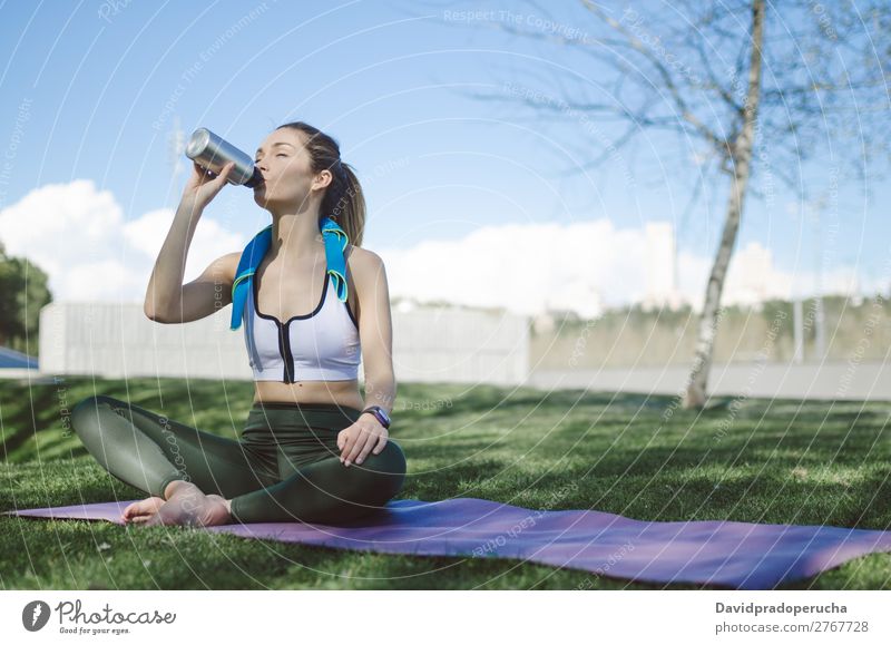 Frau ruht sich aus und trinkt Wasser mit Handtuch nach dem Training. Lifestyle schön Körper Erholung Meditation Sport Yoga Mensch Erwachsene Natur Wärme Park