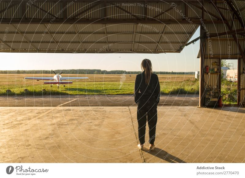 Frau, die im Hangar posiert. Körperhaltung Luftverkehr Beruf Ferien & Urlaub & Reisen heiter Freiheit Verkehr Jugendliche Abenteuer Landschaft Freizeit & Hobby