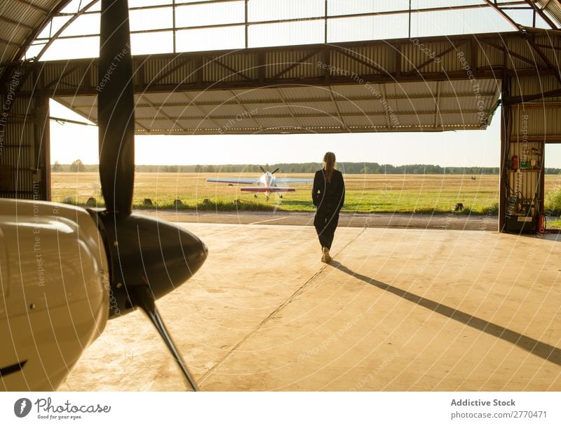 Frau, die im Hangar posiert. Körperhaltung Luftverkehr Beruf Ferien & Urlaub & Reisen heiter Freiheit Verkehr Jugendliche Abenteuer Landschaft Freizeit & Hobby