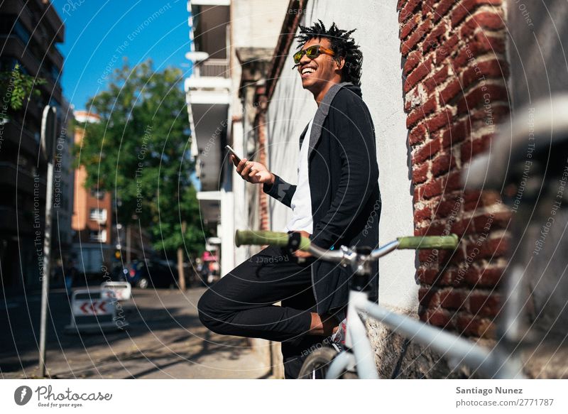 Afrojunger Mann mit Handy und festem Fahrrad. Jugendliche Afrikanisch schwarz Mulatte Afro-Look Mobile Fixie Telefon Lifestyle stehen Fahrradfahren benutzend