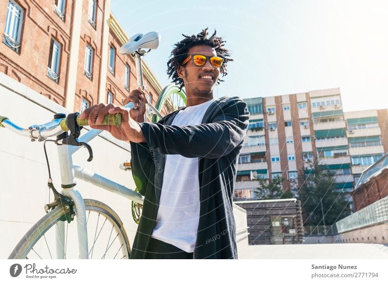 Gutaussehender Afro-Mann auf einem Fahrrad. Jugendliche Afro-Look schwarz Mulatte Afrikanisch Fixie Schickimicki Lifestyle Fahrradfahren Großstadt Stadt Mensch