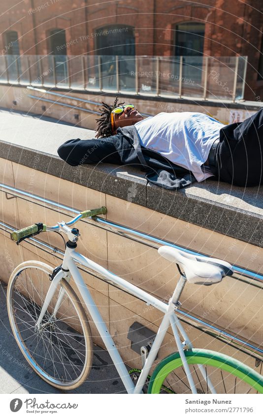 Ein gutaussehender Afro-Mann, der sich in der Nähe seines Fahrrads entspannt. Fixie Schickimicki Lifestyle laufen lügen Erholung genießend Fahrradfahren