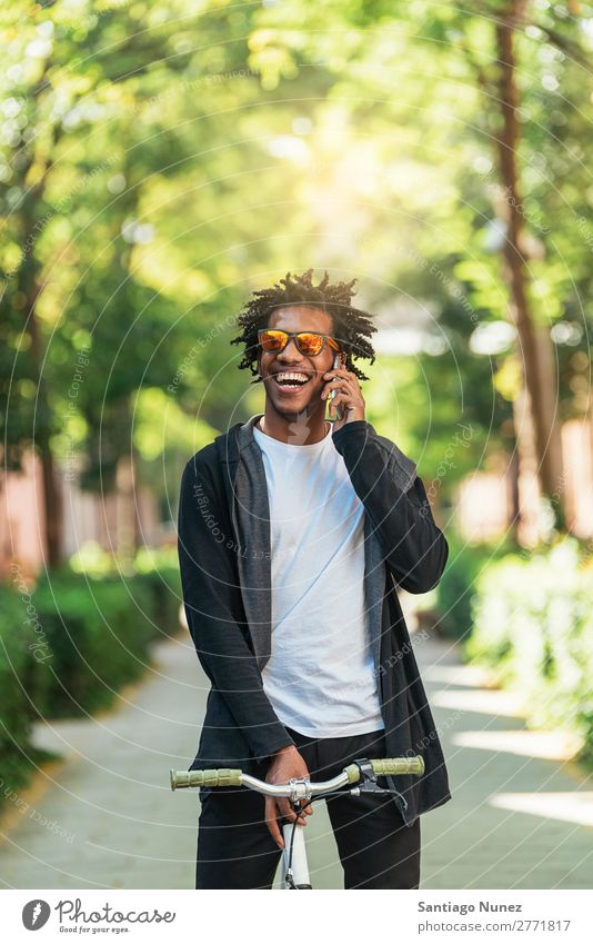 Afrojunger Mann mit Handy und festem Fahrrad. Jugendliche Afrikanisch schwarz Mulatte Afro-Look Mobile Fixie Telefon Lifestyle stehen Fahrradfahren benutzend