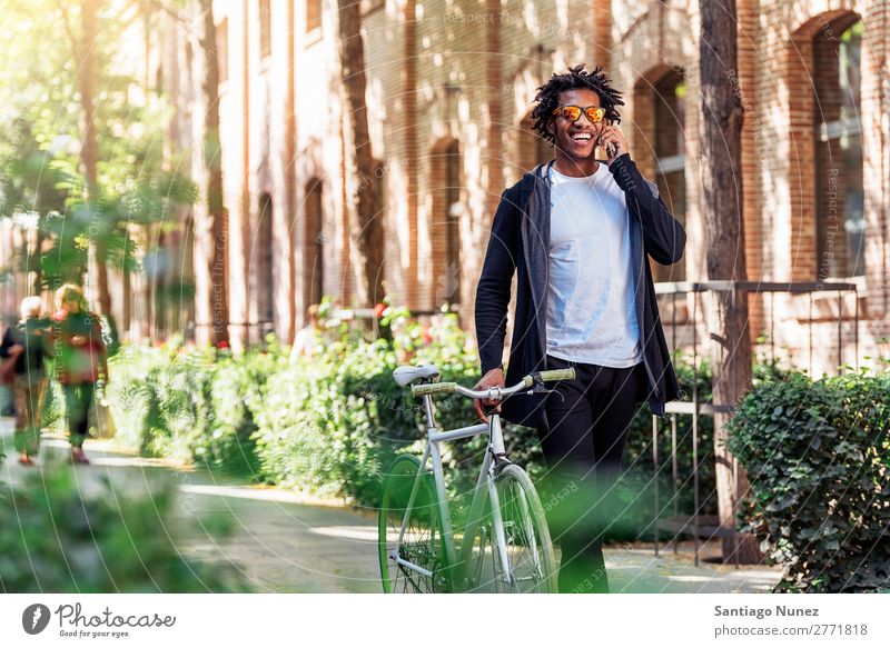 Afrojunger Mann mit Handy und festem Fahrrad. Jugendliche Afrikanisch schwarz Mulatte Afro-Look Mobile Fixie Telefon Lifestyle stehen Fahrradfahren benutzend