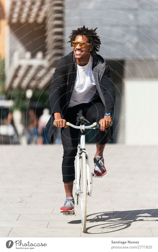 Gutaussehender Afro-Mann auf einem Fahrrad. Jugendliche Afro-Look schwarz Mulatte Afrikanisch Fixie Schickimicki Lifestyle Fahrradfahren Großstadt Stadt Mensch