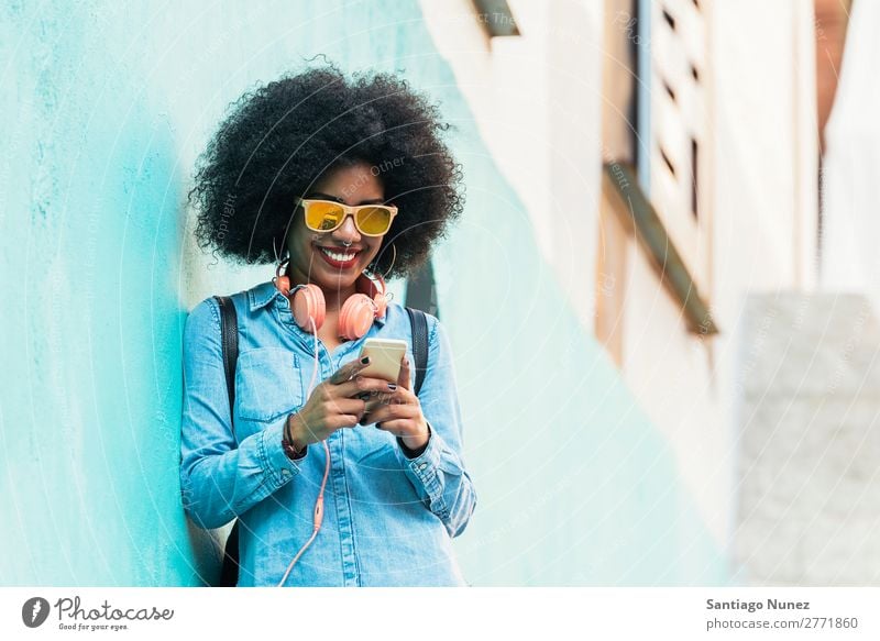 Schöne afroamerikanische Frau, die ein Handy auf der Straße benutzt. schwarz Afrikanisch Afro-Look Mensch Porträt PDA Jugendliche Mobile Telefon Chatten Texten