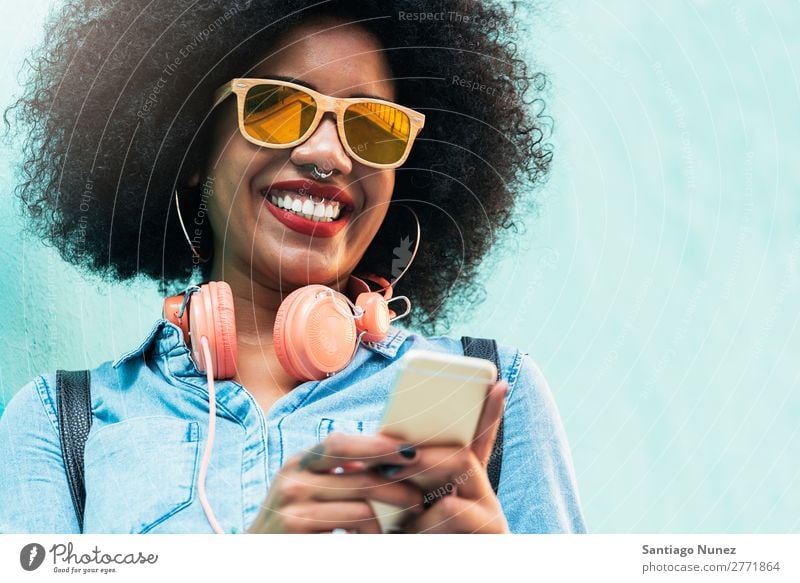 Schöne afroamerikanische Frau, die ein Handy auf der Straße benutzt. schwarz Afrikanisch Afro-Look Mensch Porträt PDA Jugendliche Mobile Telefon Chatten Texten