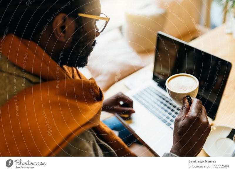 Geschäftsmann mit seinem Laptop im Coffee Shop. Mann schwarz Afrikanisch Amerikaner Business Handy Jugendliche Notebook Computer Coffee-Shop Kaffee Büro Mensch