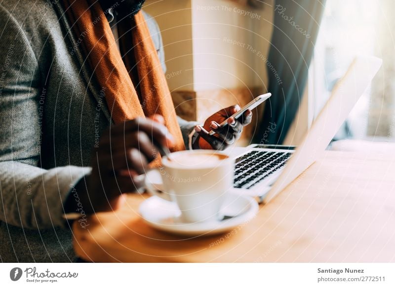 Geschäftsmann mit seinem Laptop im Coffee Shop. Mann schwarz Afrikanisch Amerikaner Business Handy Jugendliche Notebook Computer Coffee-Shop Kaffee Büro Mensch