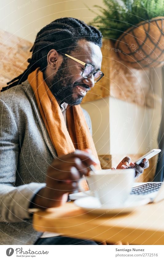 Geschäftsmann mit seinem Laptop im Coffee Shop. Mann schwarz Afrikanisch Amerikaner Business Handy Jugendliche Notebook Computer Glück Büro Mensch