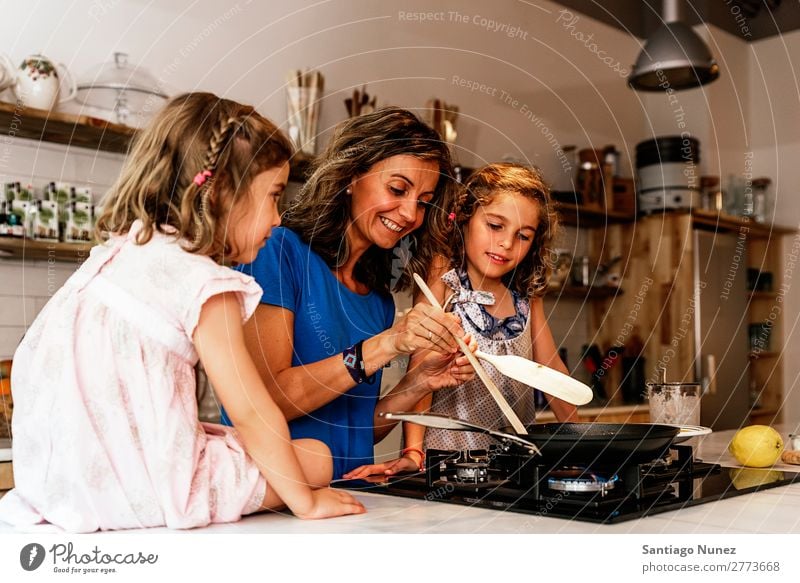 Kleine Schwestern kochen mit ihrer Mutter in der Küche. Kind Mädchen kochen & garen Koch Schokolade Speiseeis Tochter Tag Glück Freude Familie & Verwandtschaft