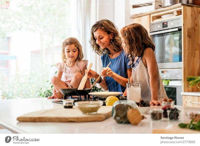 Kleine Schwestern kochen mit ihrer Mutter in der Küche. Kind Mädchen kochen & garen Koch Schokolade Speiseeis Tochter Tag Glück Freude Familie & Verwandtschaft