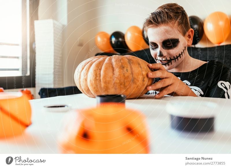 Ein fröhlicher Junge verkleidet, der zu Hause einen Kürbis schmückt. Halloween Kind malen Skelett Freude Familie & Verwandtschaft Hermano Porträt Angst