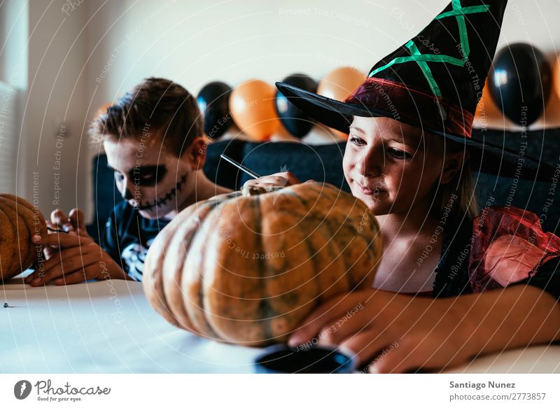 Glückliche Kinder verkleideten sich und schmückten zu Hause einen Kürbis. Halloween Mädchen Junge malen Skelett Hexe Freude Familie & Verwandtschaft Schwester