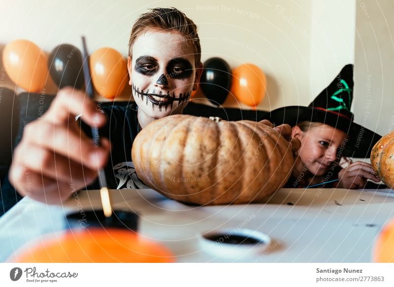 Glückliche Kinder verkleideten sich und schmückten zu Hause einen Kürbis. Halloween Mädchen Junge malen Skelett Hexe Freude Familie & Verwandtschaft Schwester