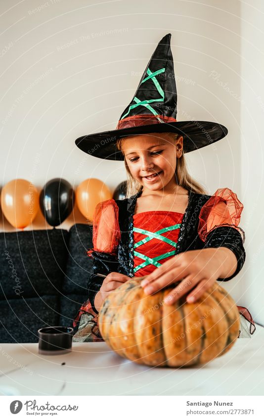 Schönes Mädchen verkleidet von einer Hexe, die zu Hause einen Kürbis schmückt. Halloween Kind malen Freude Familie & Verwandtschaft Schwester Porträt Angst