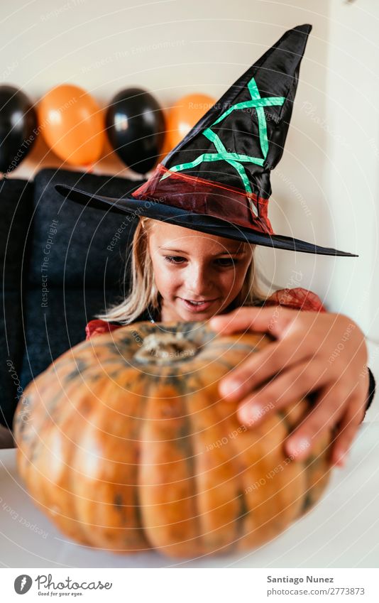 Schönes Mädchen verkleidet von einer Hexe, die zu Hause einen Kürbis schmückt. Halloween Kind malen Freude Familie & Verwandtschaft Schwester Porträt Angst