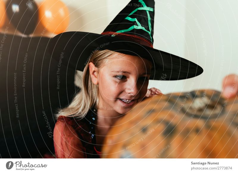 Schönes Mädchen verkleidet von einer Hexe, die zu Hause einen Kürbis schmückt. Halloween Kind malen Freude Familie & Verwandtschaft Schwester Porträt Angst