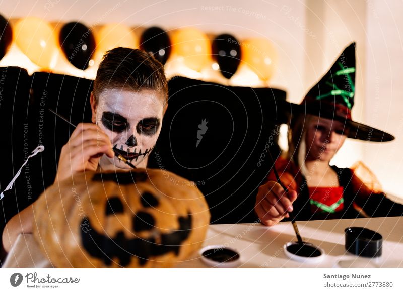 Glückliche Kinder verkleideten sich und schmückten zu Hause einen Kürbis. Halloween Mädchen Junge malen Skelett Hexe Freude Familie & Verwandtschaft Schwester