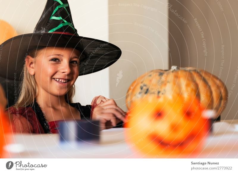 Schönes Mädchen verkleidet von einer Hexe, die zu Hause einen Kürbis schmückt. Halloween Kind malen Freude Familie & Verwandtschaft Schwester Porträt Angst