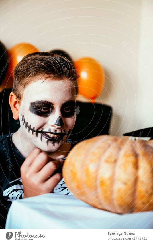 Ein fröhlicher Junge verkleidet, der zu Hause einen Kürbis schmückt. Halloween Kind malen Skelett Freude Familie & Verwandtschaft Hermano Porträt Angst