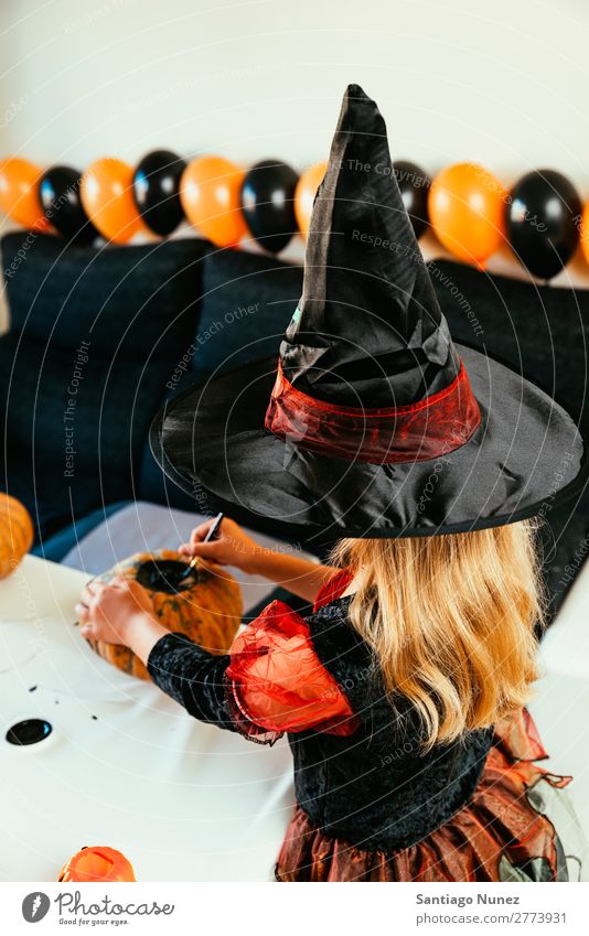 Schönes Mädchen verkleidet von einer Hexe, die zu Hause einen Kürbis schmückt. Halloween Kind malen Freude Familie & Verwandtschaft Schwester Porträt Angst