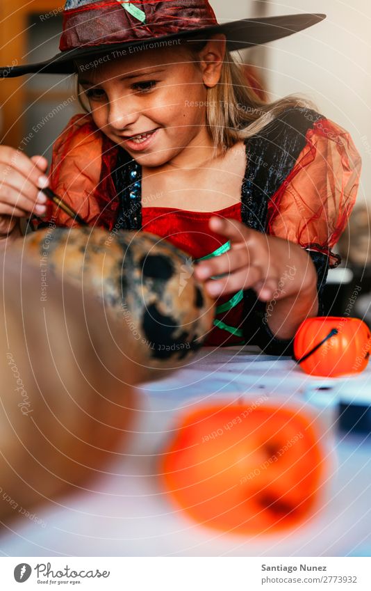 Schönes Mädchen verkleidet von einer Hexe, die zu Hause einen Kürbis schmückt. Halloween Kind malen Freude Familie & Verwandtschaft Schwester Porträt Angst