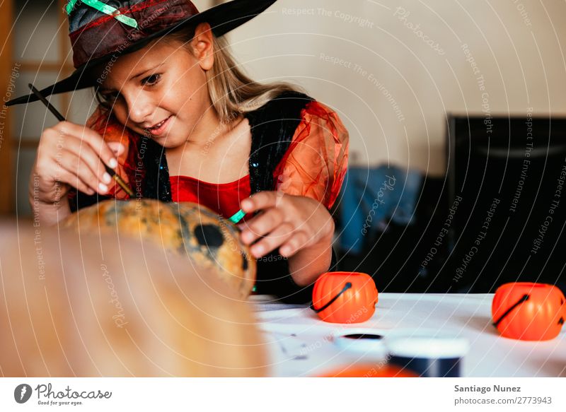 Schönes Mädchen verkleidet von einer Hexe, die zu Hause einen Kürbis schmückt. Halloween Kind malen Freude Familie & Verwandtschaft Schwester Porträt Angst