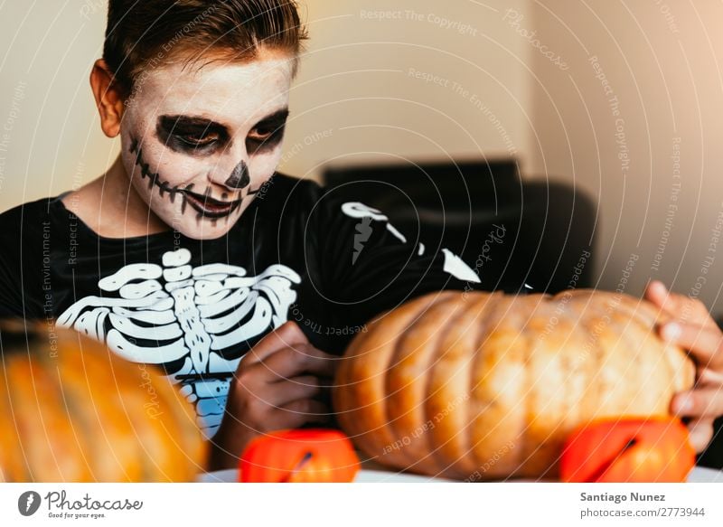 Ein fröhlicher Junge verkleidet, der zu Hause einen Kürbis schmückt. Halloween Kind malen Skelett Freude Familie & Verwandtschaft Hermano Porträt Angst