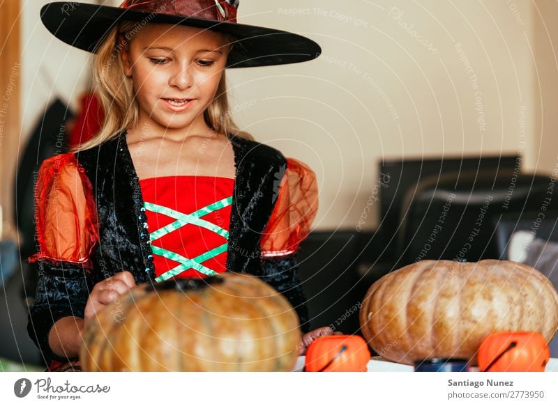 Schönes Mädchen verkleidet von einer Hexe, die zu Hause einen Kürbis schmückt. Halloween Kind malen Freude Familie & Verwandtschaft Schwester Porträt Angst