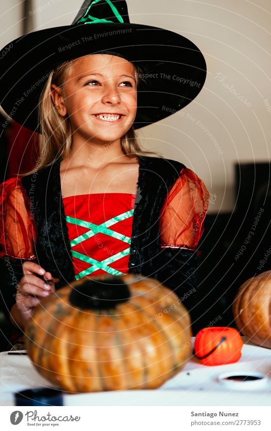 Schönes Mädchen verkleidet von einer Hexe, die zu Hause einen Kürbis schmückt. Halloween Kind malen Freude Familie & Verwandtschaft Schwester Porträt Angst