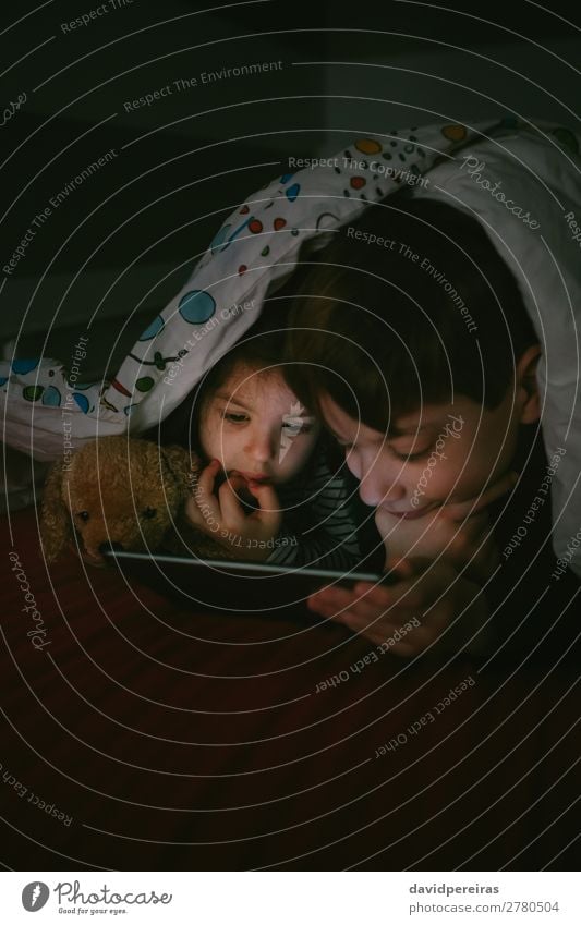 Kinder auf dem Bett liegend mit Blick auf die Tafel Lifestyle Gesicht Windstille Spielen Schlafzimmer Technik & Technologie Internet Mensch Junge Frau