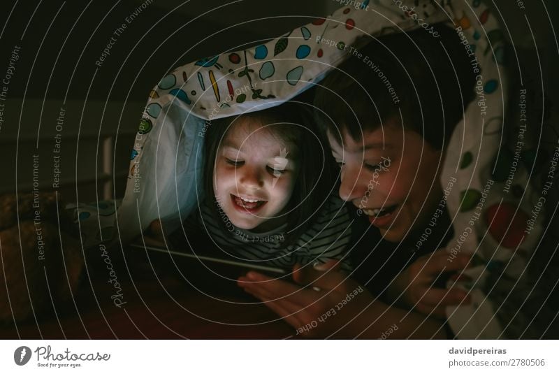 Brüder, die die Tafel im Dunkeln betrachten. Freude Glück Gesicht Spielen Schlafzimmer Kind Technik & Technologie Internet Mensch Junge Frau Erwachsene Mann