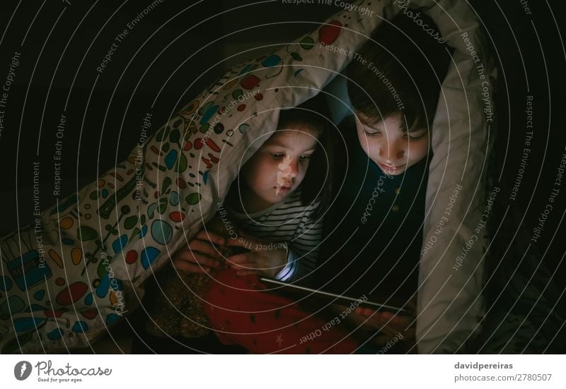 Kinder, die auf dem Bett sitzen und im Dunkeln auf das Tablett schauen Lifestyle Gesicht Windstille Spielen Schlafzimmer Technik & Technologie Internet Mensch