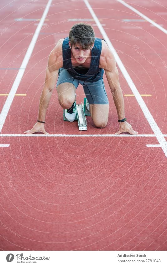 Entschlossener Sportler beim Kauerstart Läufer Rennbahn Sprinter Biegen Stadion Erfolg Fitness üben Athlet muskulös Erwachsene Sportbekleidung sportlich