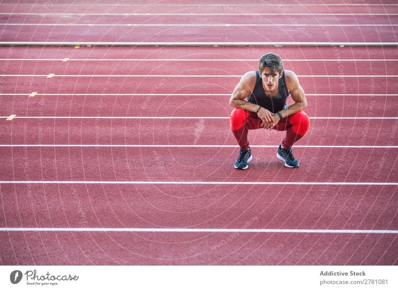 Sportler auf der Rennstrecke sitzend Mann Rennbahn ruhen Körperhaltung Kniebeuge Fitness üben Athlet muskulös Erholung Erwachsene Stadion Sprinter Pause