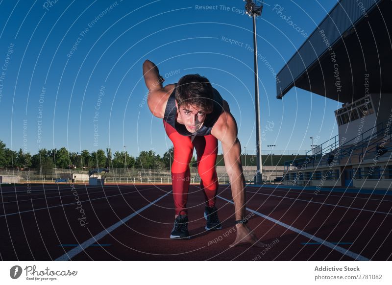 Junger männlicher Sprinter bereit zum Laufen Mann Kauerstart Rennbahn Konzentration Stadion sportlich Fitness Sommer Athlet Sport Erwachsene Sportbekleidung