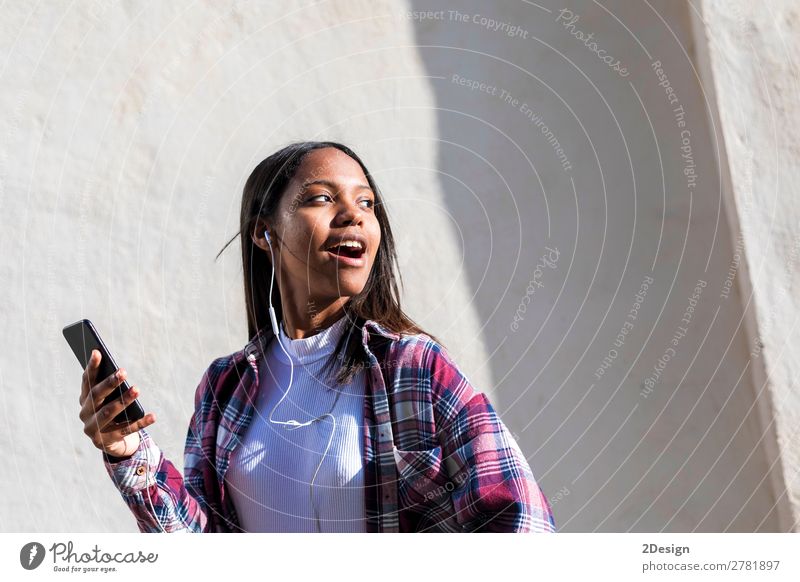 Vorderansicht einer jungen lächelnden Afroamerikanerin im Stehen Lifestyle Glück schön Entertainment Musik Telefon Mensch feminin Junge Frau Jugendliche