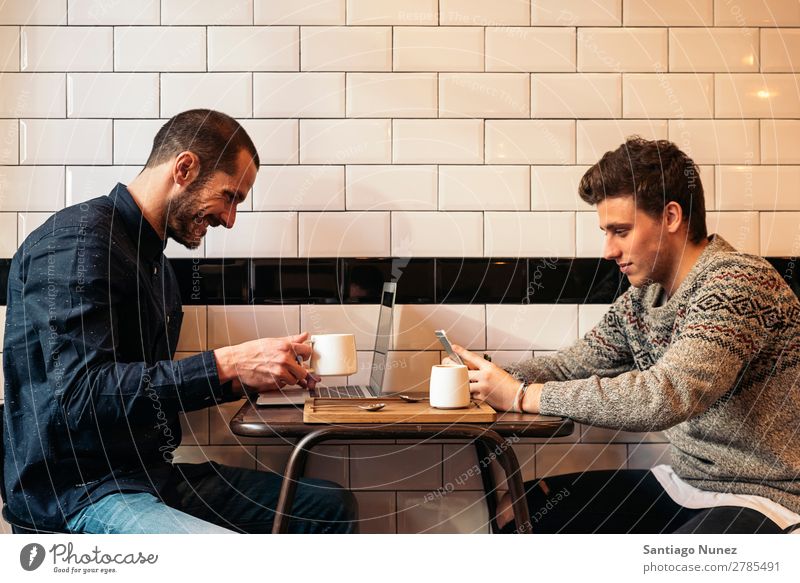 Freunde, die Handy und Laptop benutzen. Mann Kaffee Freundschaft Jugendliche Teamwork Menschengruppe Lifestyle PDA Mobile Mitteilung benutzend Text Computer