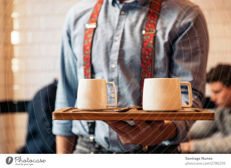 Der Kellner hält ein Tablett mit Kaffee. Kellnern Kantine Portion Café Barista kaufen Angebot Tasse schließen Aufschlag nach oben Server Jugendliche Aussicht